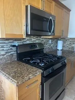 a kitchen with granite countertop a stove and a microwave