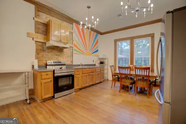 a kitchen with stainless steel appliances granite countertop a stove top oven a sink dishwasher and a dining table with wooden floor