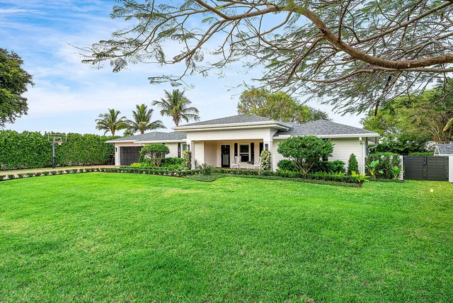a view of a white house with potted plants and a table and chairs