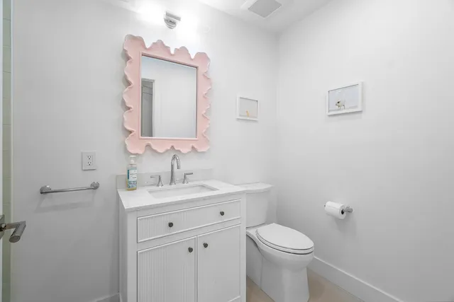 a bathroom with a toilet sink vanity and mirror