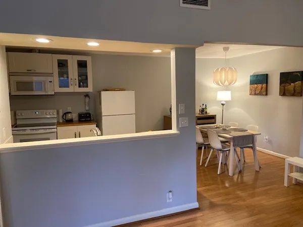 a living room with couches and kitchen view with wooden floor