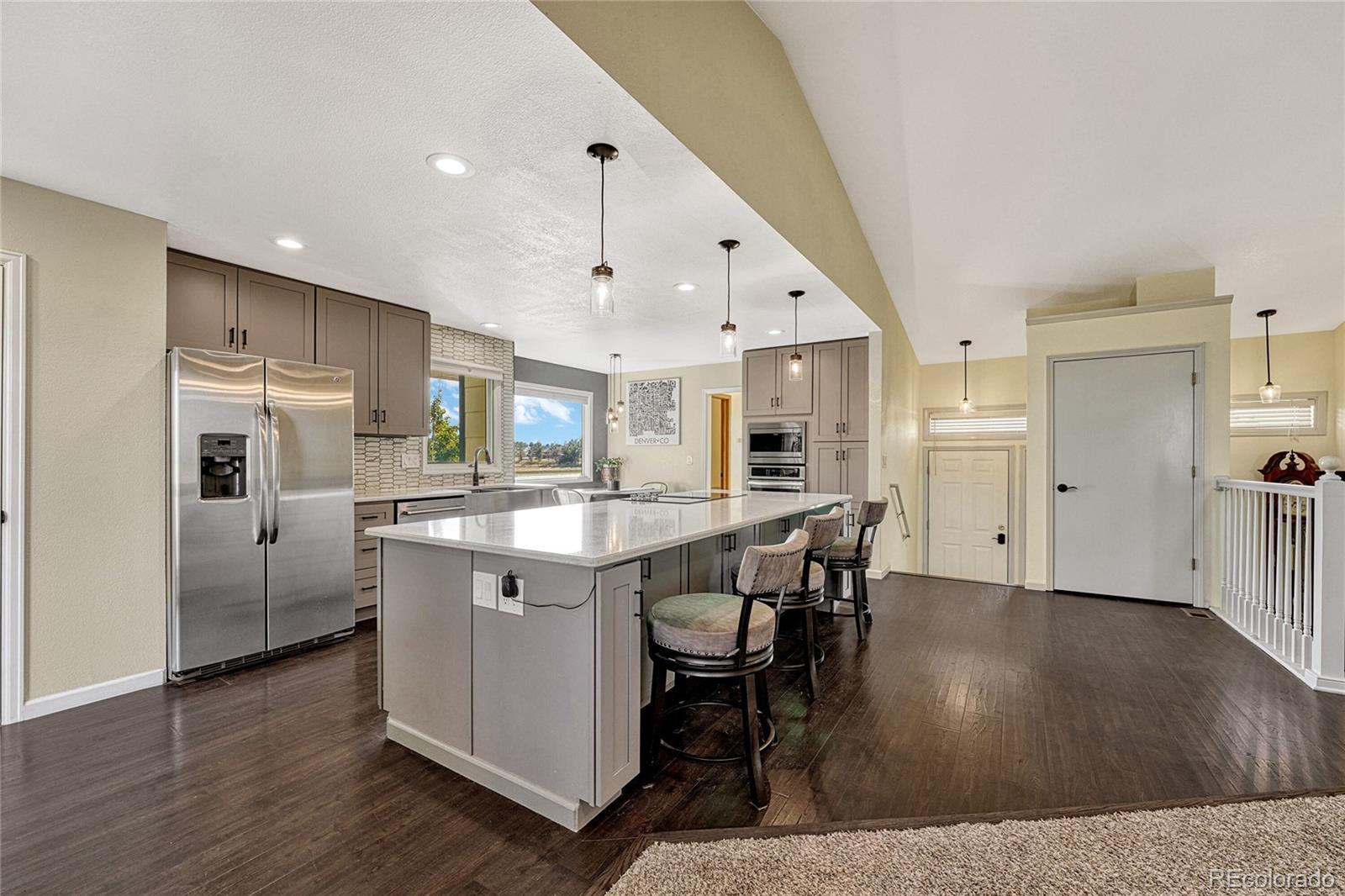 2460 Eileen Way Parker, CO 80138 - Photo 6 of 47 a kitchen with stainless steel appliances granite countertop a sink a stove a refrigerator and a dining table with wooden floor