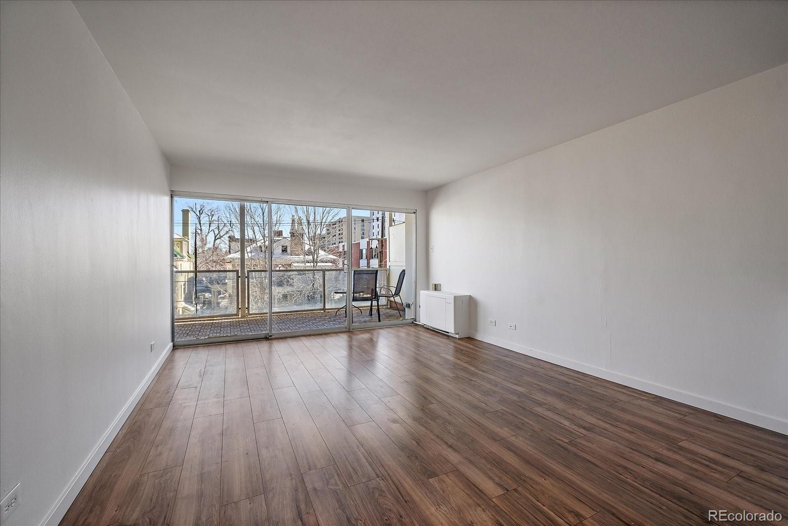 888 Logan Street, Unit 4F Denver, CO 80203 - Photo 4 of 21 wooden floor in an empty room with a window