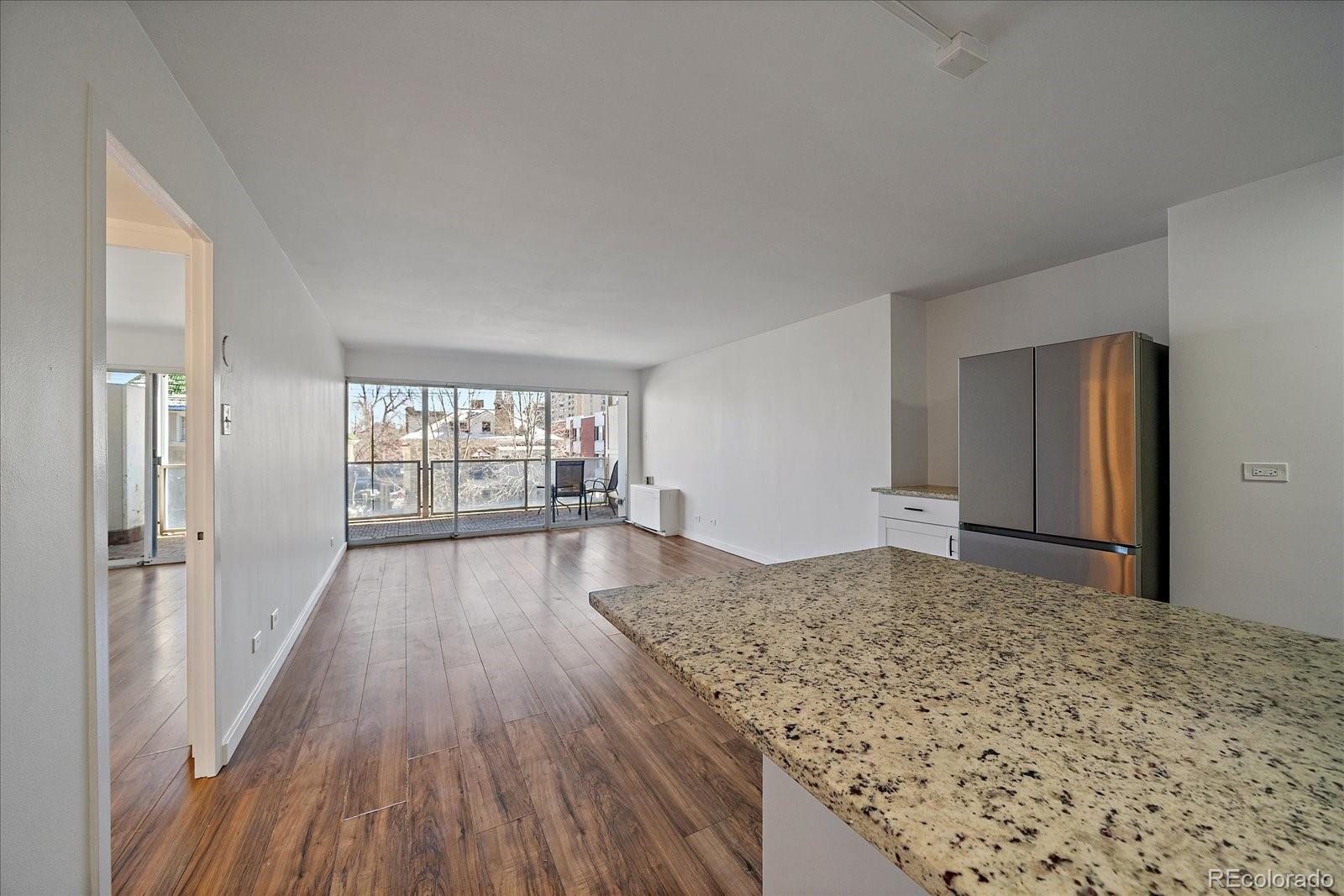 888 Logan Street, Unit 4F Denver, CO 80203 - Photo 5 of 21 a view of empty room with wooden floor and kitchen view