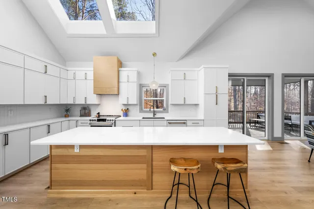 a large kitchen with kitchen island a counter top space a sink stainless steel appliances and cabinets