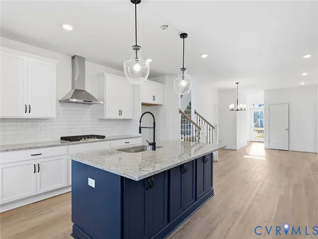 a kitchen with stainless steel appliances granite countertop a sink a stove a refrigerator and island with wooden floor