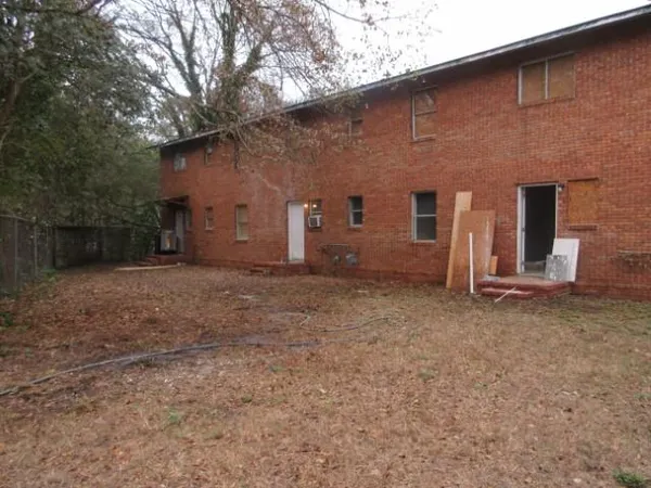 a backyard of a house with large trees and brick walls