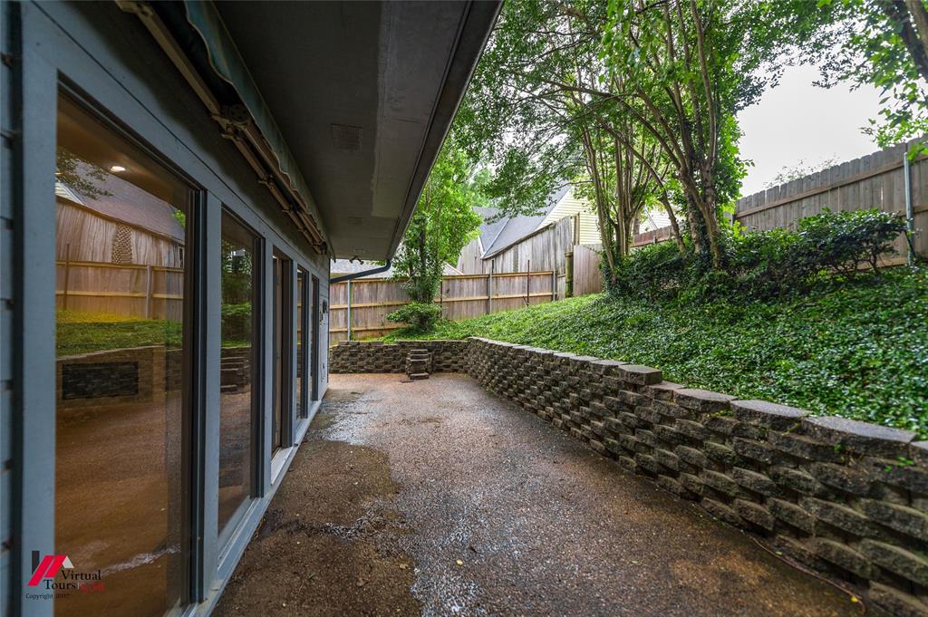 300 Pierremont Road, Unit 40 Shreveport, LA 71106 - Photo 34 of 34 Expansive patio area featuring a retaining wall, mature trees, and privacy fencing