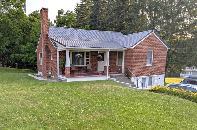 a view of a house with a yard and a large tree