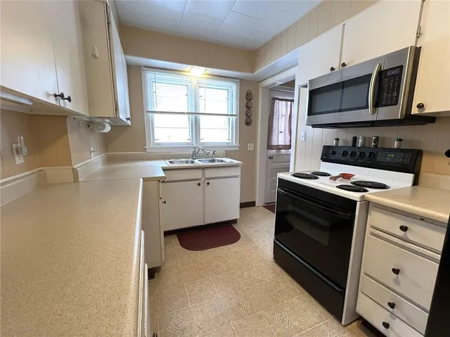 a kitchen with stainless steel appliances a stove microwave and sink