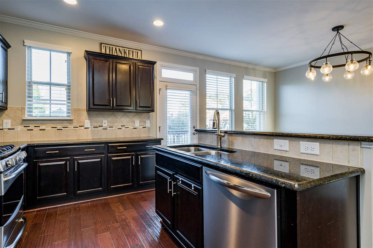 1521 Rodessa Run Raleigh, NC 27607 - Photo 17 of 29 Kitchen features easy island/bar for eating/cooking/hanging out. Granite counters, stainless appliances, full pantry with wooden shelving, ceramic tile backsplash and the loved dark cabinets. Kitchen