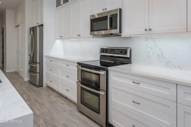 a kitchen with stainless steel appliances white cabinets and a stove a oven with wooden floor