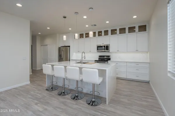 a large white kitchen with kitchen island white cabinets and stainless steel appliances
