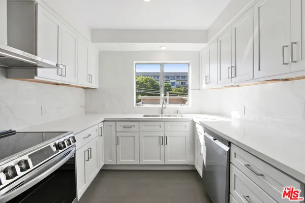 a kitchen with white cabinets appliances a sink and a window