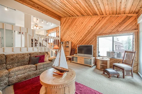 a living room with furniture a flat screen tv and a floor to ceiling window