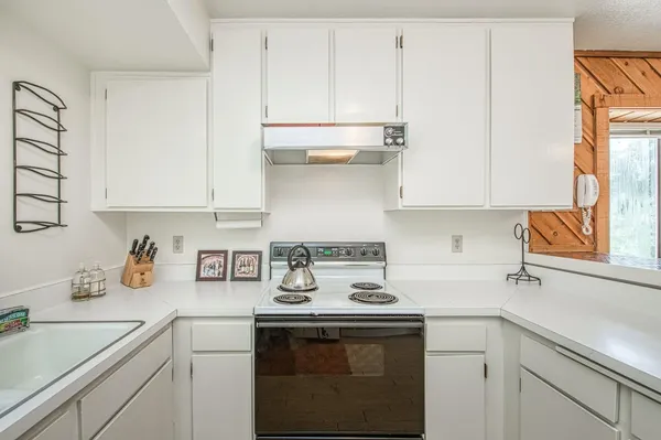 a kitchen with stainless steel appliances granite countertop a sink a stove and white cabinets