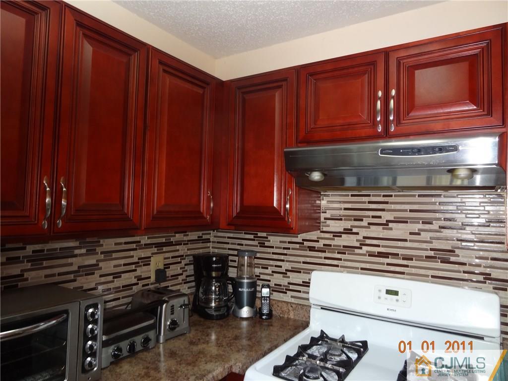 1019 Edpas Road, Unit 1019 New Brunswick, NJ 08901 - Photo 4 of 18 a kitchen with wooden cabinets and a stove top oven