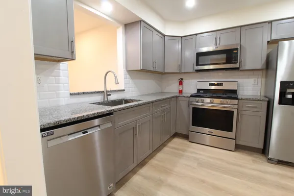 a kitchen with stainless steel appliances granite countertop a stove a sink and a microwave