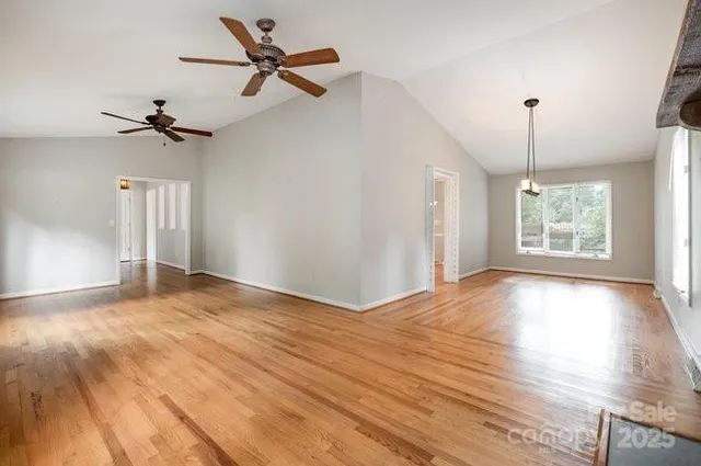 a view of an empty room with window and wooden floor