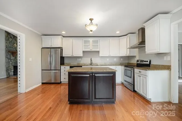 a kitchen with stainless steel appliances granite countertop a refrigerator a sink dishwasher a stove and white countertops with wooden floor