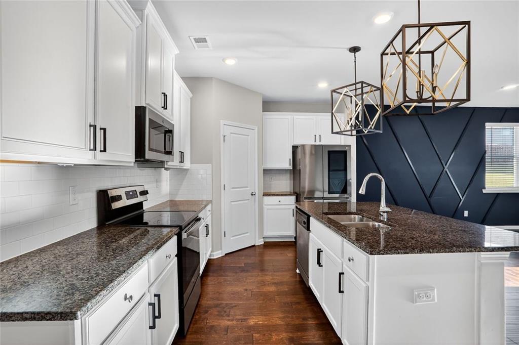 1553 Spring Hollow Way Stone Mountain, GA 30083 - Photo 4 of 25 a kitchen with stainless steel appliances granite countertop a sink a stove and a wooden cabinets