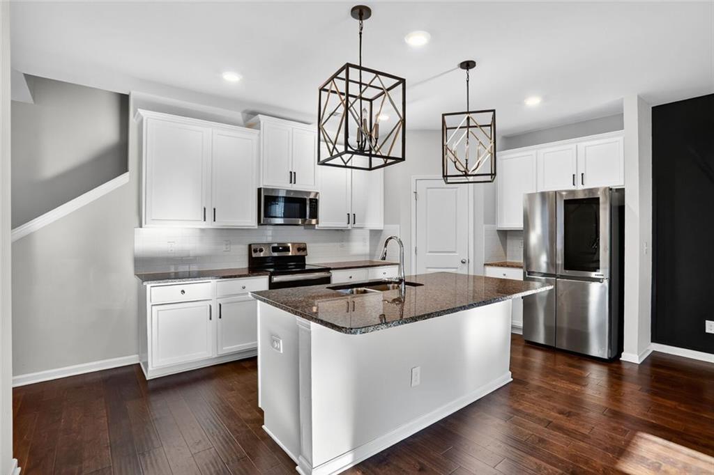 1553 Spring Hollow Way Stone Mountain, GA 30083 - Photo 5 of 25 a kitchen with stainless steel appliances granite countertop a refrigerator a sink dishwasher a stove and white cabinets with wooden floor