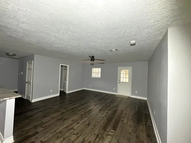 a view of an empty room with window and wooden floor