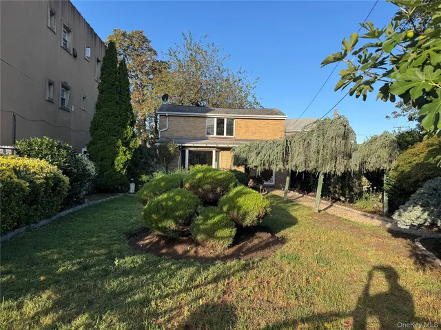 a front view of a house with a yard and tree s