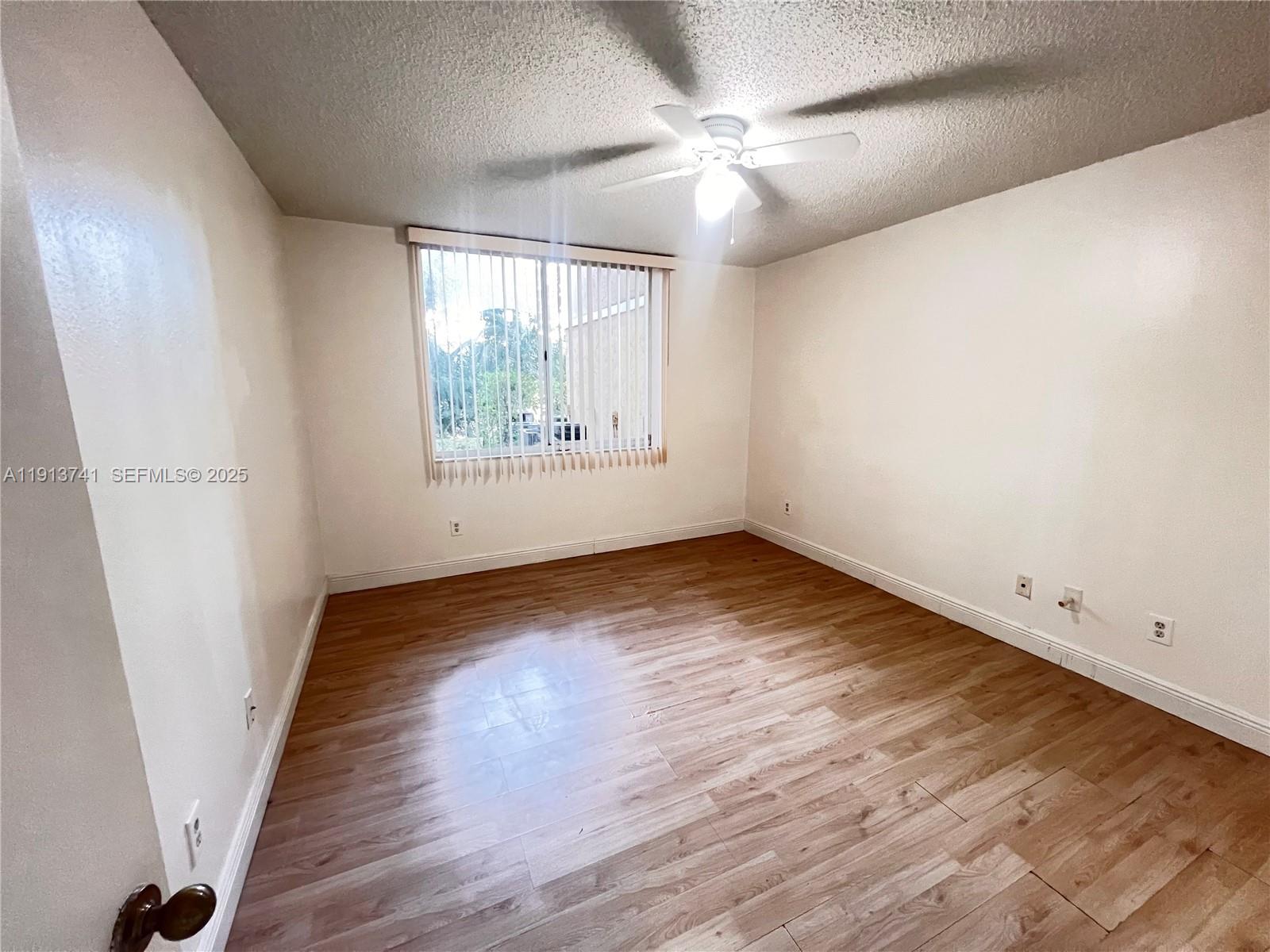 4055 West McNab Road, Unit H104 Pompano Beach, FL 33069 - Photo 6 of 14 an empty room with wooden floor and windows