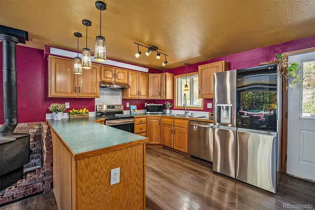 a kitchen with kitchen island granite countertop a stove a sink dishwasher and a refrigerator with wooden cabinets