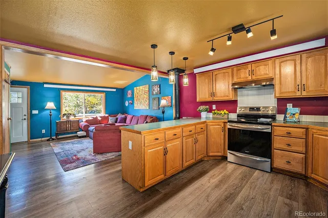 a large kitchen with stainless steel appliances granite countertop a stove and a wooden floors