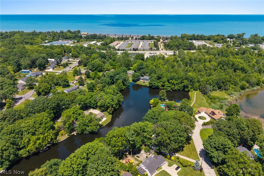 685 Sunnyside Road Vermilion, OH 44089 - Photo 46 of 50 Expansive aerial establishing verdant surroundings with mature trees, a tranquil lake, and distant azure water