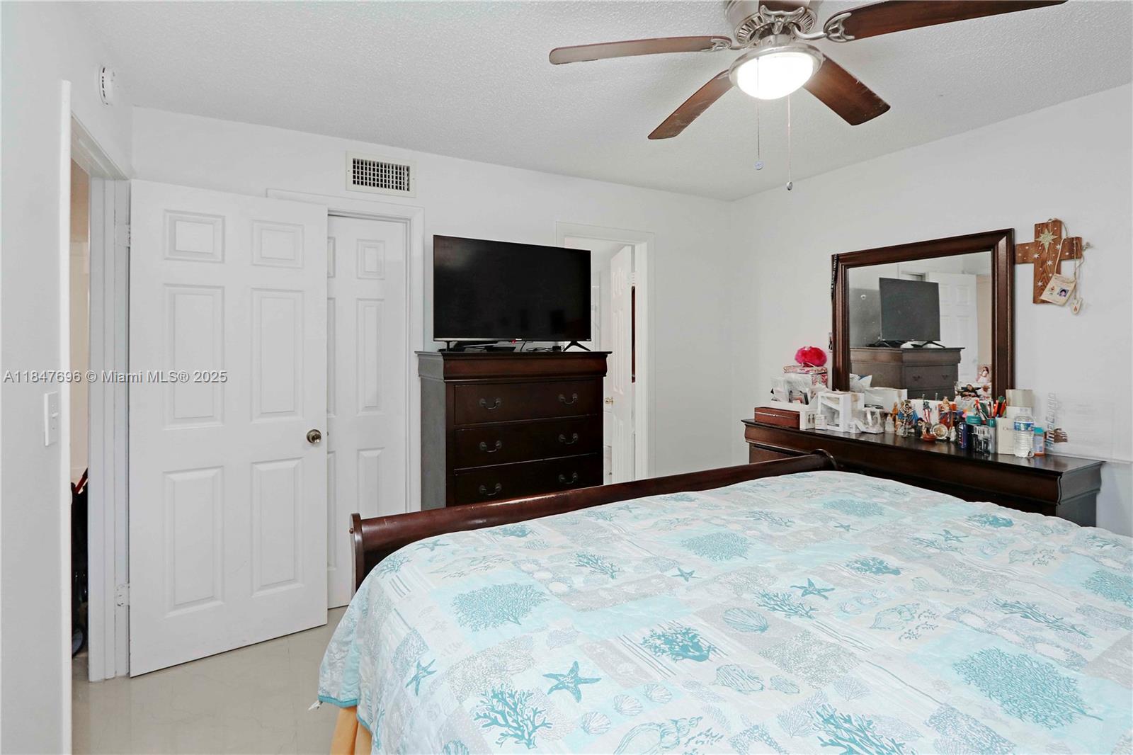 9917 West Okeechobee Road, Unit 3303 Hialeah Gardens, FL 33016 - Photo 17 of 26 a bedroom with a bed and a flat tv screen on dresser