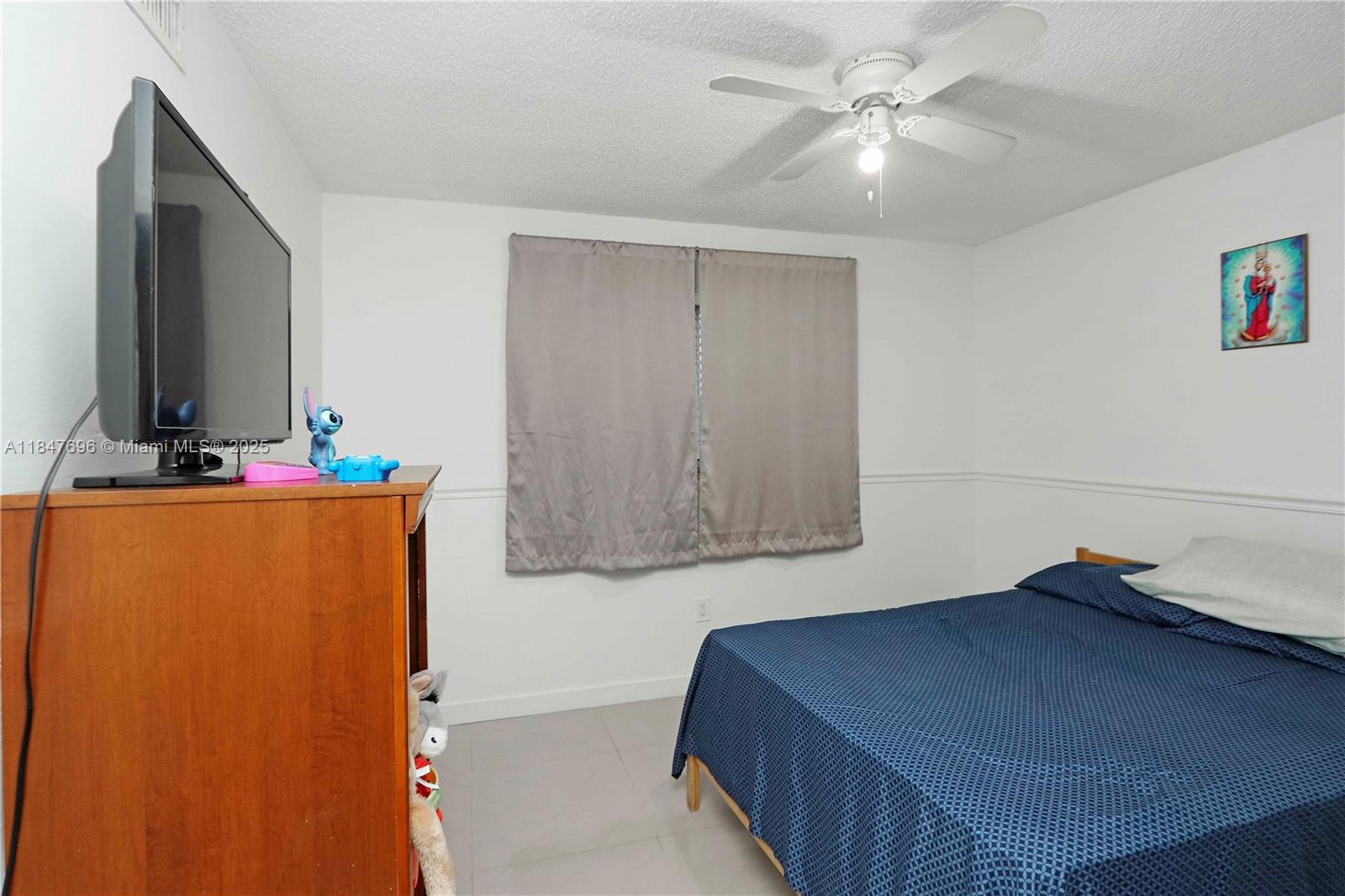 9917 West Okeechobee Road, Unit 3303 Hialeah Gardens, FL 33016 - Photo 20 of 26 a bedroom with a bed and a flat screen tv