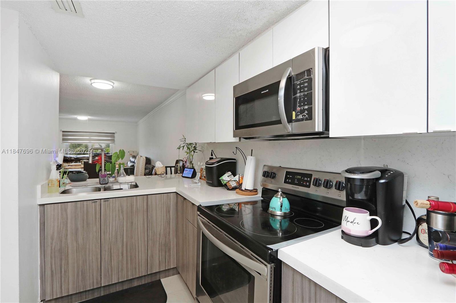 9917 West Okeechobee Road, Unit 3303 Hialeah Gardens, FL 33016 - Photo 2 of 26 a kitchen with a sink a stove and cabinets