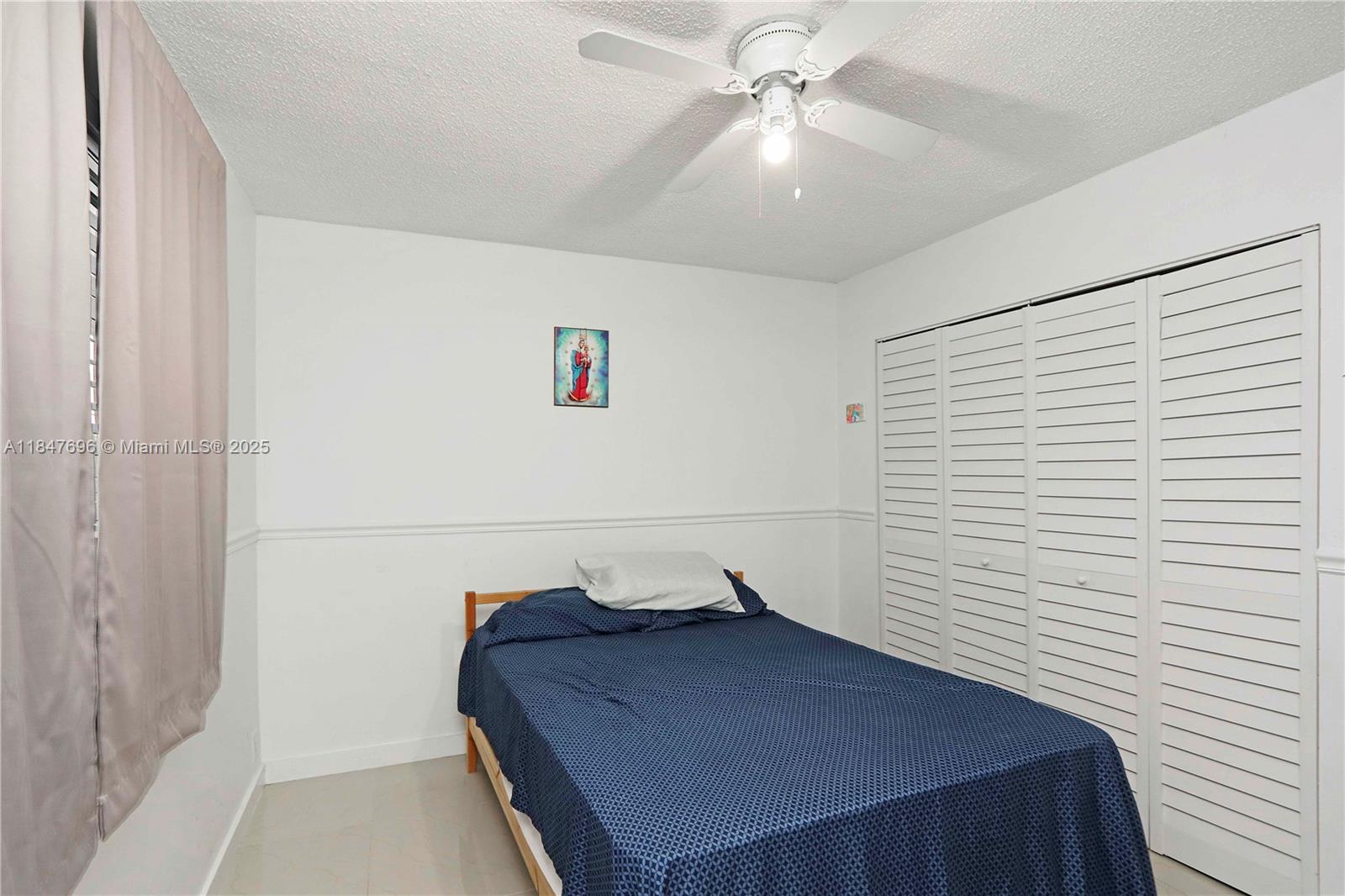 9917 West Okeechobee Road, Unit 3303 Hialeah Gardens, FL 33016 - Photo 21 of 26 a bedroom with a bed and a ceiling fan