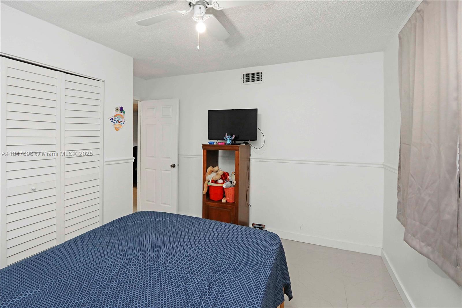 9917 West Okeechobee Road, Unit 3303 Hialeah Gardens, FL 33016 - Photo 22 of 26 a bedroom with a bed and a flat screen tv