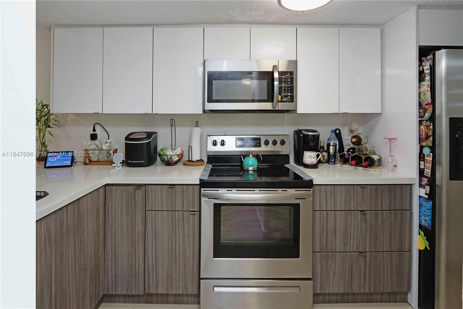 9917 West Okeechobee Road, Unit 3303 Hialeah Gardens, FL 33016 - Photo 5 of 26 a kitchen with stainless steel appliances granite countertop a stove a microwave and cabinets