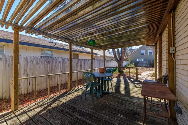 a view of a patio with table and chairs with wooden floor and fence