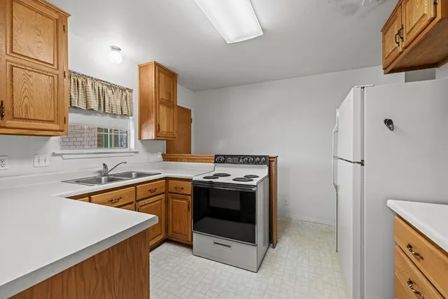 a kitchen that has a sink a stove and a refrigerator