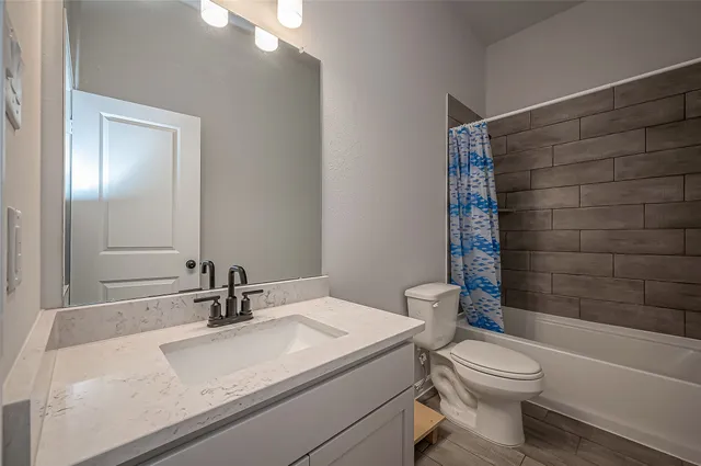 a bathroom with a granite countertop sink a toilet and shower