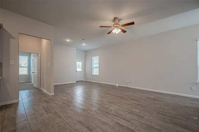 a view of empty room with wooden floor and fan