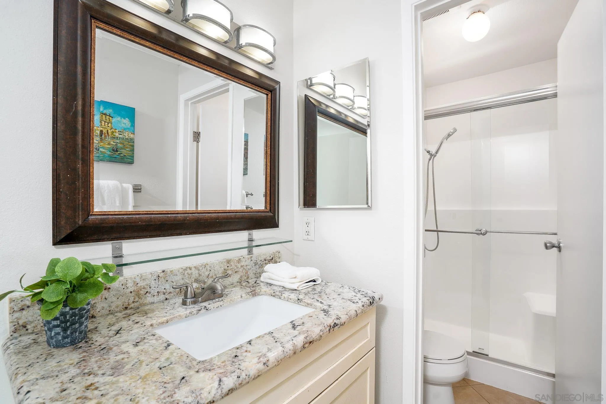6069 Rancho Mission Road, Unit 201 San Diego, CA 92108 - Photo 21 of 43 a bathroom with a granite countertop sink a toilet and a mirror