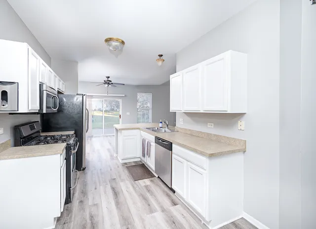 a kitchen with a sink a counter top space stainless steel appliances and cabinets
