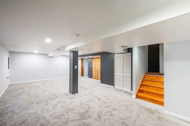 an empty room with staircase and a ceiling fan