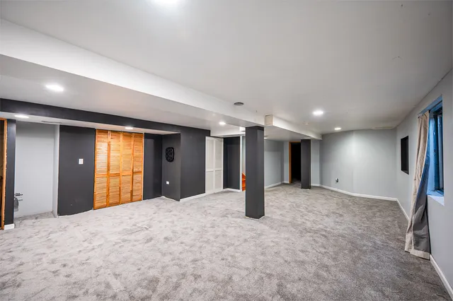 a view of an empty room with window and a kitchen