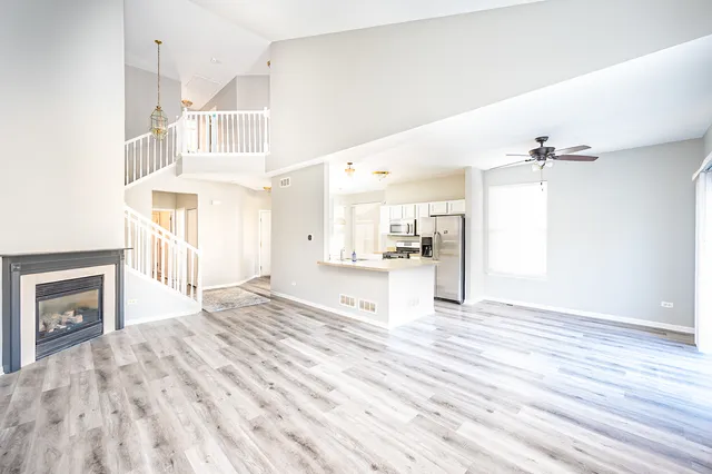 a view of an empty room with kitchen and fireplace