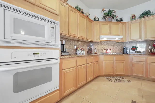 a kitchen with granite countertop white cabinets white stainless steel appliances and a sink