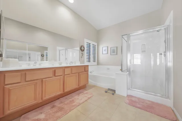 a spacious bathroom with a granite countertop sink a mirror a bathtub and next to a window