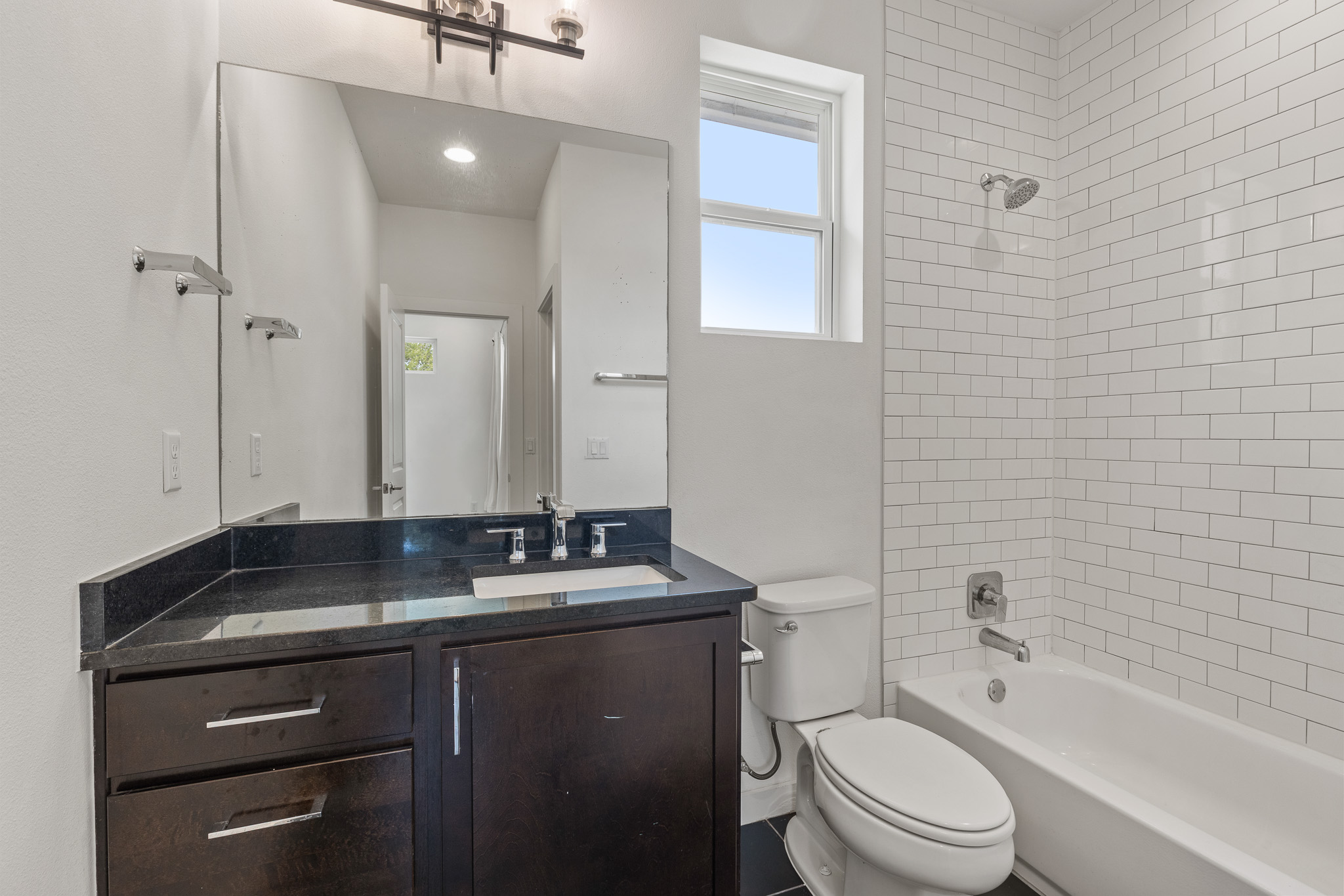 2604 Wheless Lane, Unit 1 Austin, TX 78723 - Photo 29 of 38 Spa-quality secondary bathroom features white subway tile and dark wood vanity for upscale appeal.